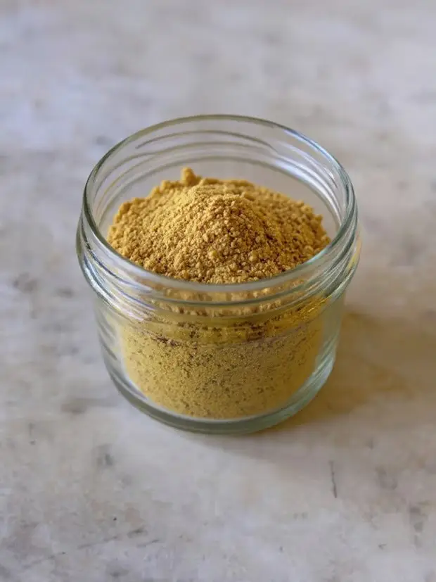 Chicken Bouillon Powder 2 Jar of homemade chicken bouillon powder with fresh herbs on a rustic wooden surface.