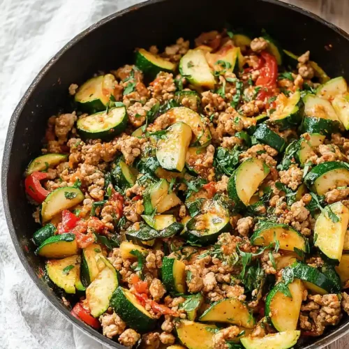 Ground turkey zucchini skillet cooking in cast iron pan with wooden spoon